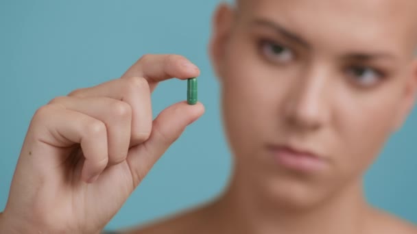 Haarlose Dame mit medizinischer Pille vor blauem Hintergrund — Stockvideo