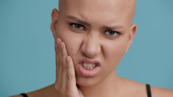 Careca de cabeça mulher sofrendo de dor de dente tocando bochecha sobre fundo azul — Vídeo de Stock