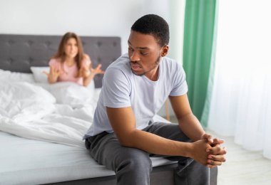 Genç siyahi adam kendini mutsuz hissediyor, evde yatakta oturuyor, karısı ona bağırıyor.