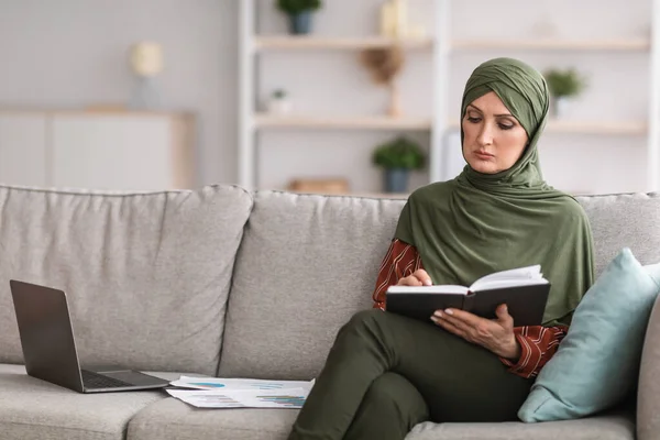 Moderna empresaria musulmana leyendo cuaderno con horario de trabajo en interiores — Foto de Stock