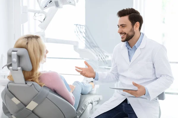 Mannelijke tandarts toont vrouwelijke patiënt x-ray op digitale tablet — Stockfoto