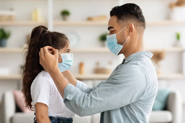 Medio oriente padre poniendo mascarilla en su hija —  Fotos de Stock