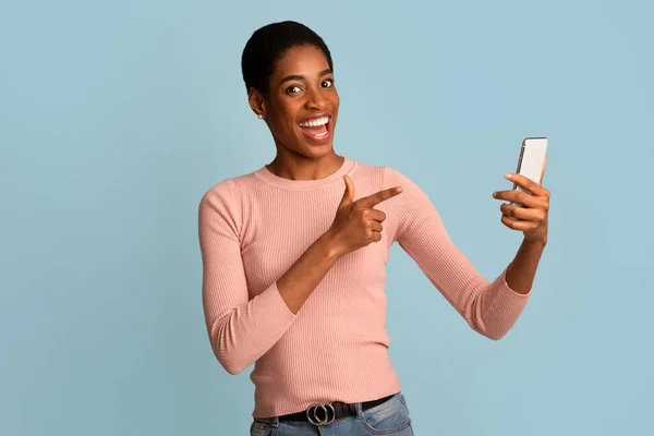 Mrkni na tuhle aplikaci. Nadšený černošky žena ukazující na smartphone v její ruce — Stock fotografie