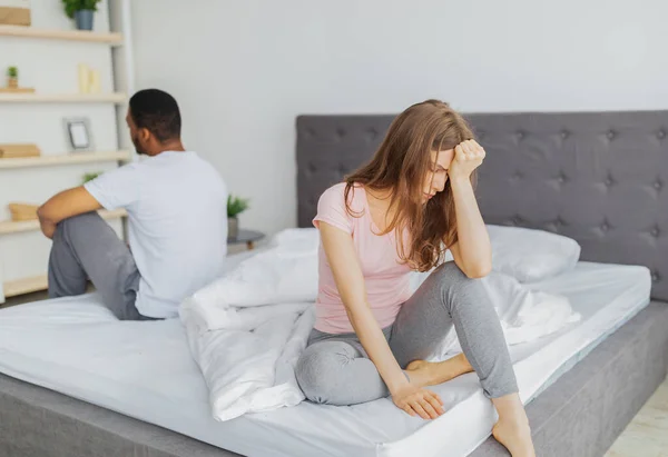 Jong interraciaal paar met relatie problemen, zitten aan weerszijden van bed, niet kijken naar elkaar — Stockfoto