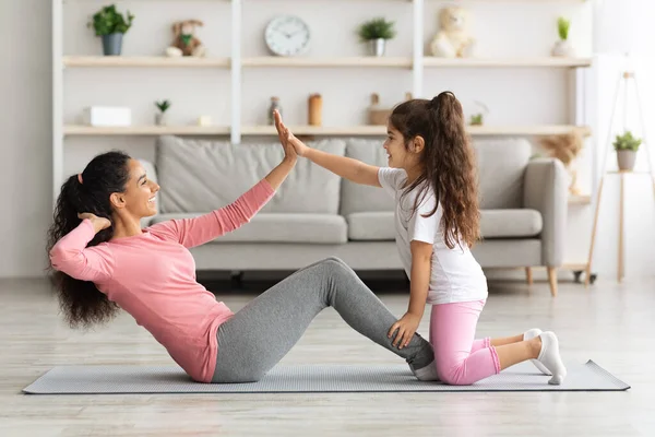 Cute mother and daughter working on abs muscles together — Stock Photo, Image