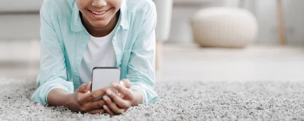Sorridente adolescente ragazza nera guarda il video online, chatta nei social network si trova sul pavimento — Foto Stock