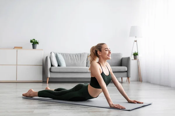 Glada glada kaukasiska ganska tusenårig blond kvinna utövar yoga, utövar ensam hemma — Stockfoto