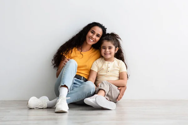 Feliz madre de Oriente Medio e hija pequeña sentadas en el piso sonriendo a la cámara —  Fotos de Stock