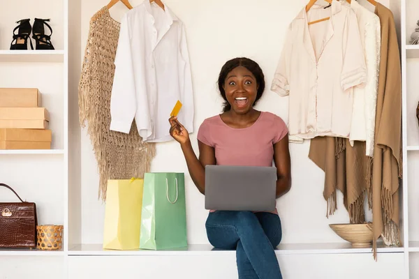 Mujer africana de compras en línea con tarjeta de crédito y ordenador portátil en interiores — Foto de Stock