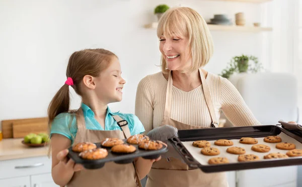 Mutlu kıdemli kadın ve torun ellerinde kurabiyelerle tepsilerle — Stok fotoğraf