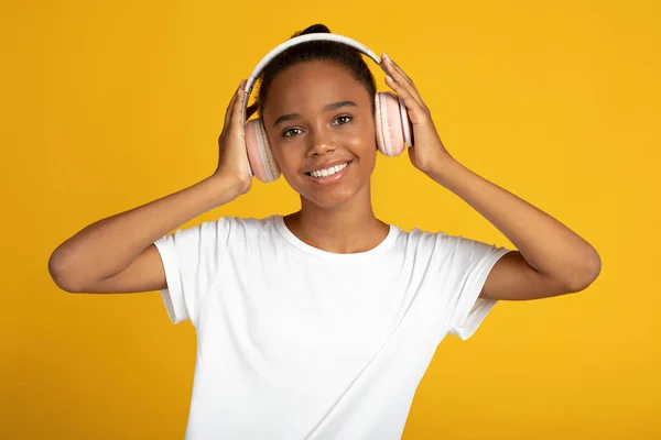 Le ung söt afrikansk-amerikansk flicka i vit t-shirt och trådlösa hörlurar lyssna musik och dans — Stockfoto