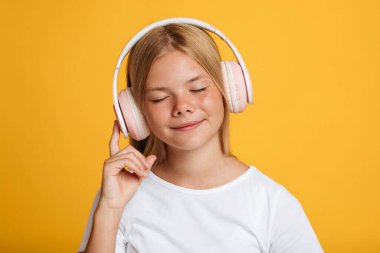 Beyaz tişörtlü, gözleri kablosuz kulaklıklı, sakin Avrupalı genç bir kadının portresi müzik dinliyor.