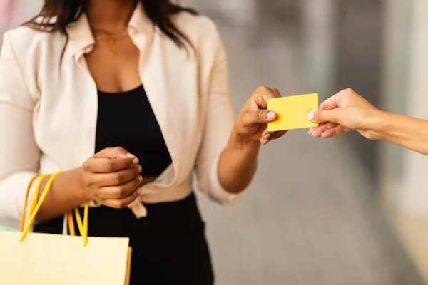 Irreconocible hembra negra dando tarjeta de crédito al vendedor — Foto de Stock