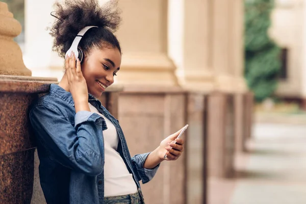 Africano giovanissima ragazza utilizzando telefono ascolto musica indossare cuffie all'aperto — Foto Stock