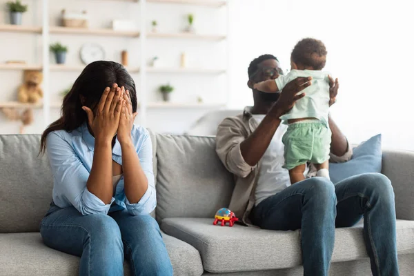 Trött afroamerikansk mamma gråter, pappa leker med barn — Stockfoto