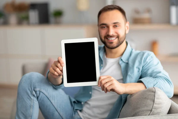 Vrolijke jongeman met tablet computer met mockup voor website of toepassing op het scherm, binnen — Stockfoto