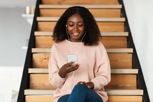 Mulher negra feliz ouvindo música no telefone em casa — Fotografia de Stock