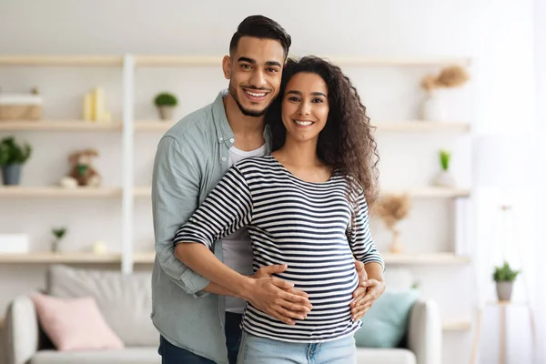 Felice uomo mediorientale che abbraccia la sua bella moglie incinta, posando insieme — Foto Stock