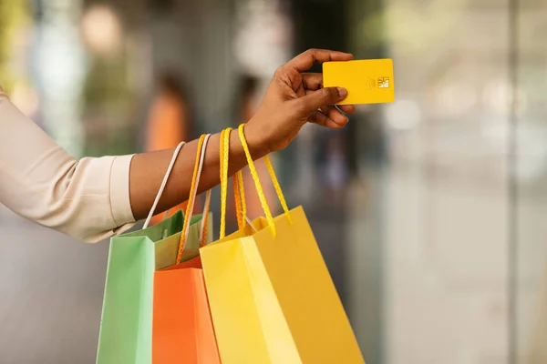 Oigenkännlig svart kvinna innehav kreditkort och shoppingväskor — Stockfoto