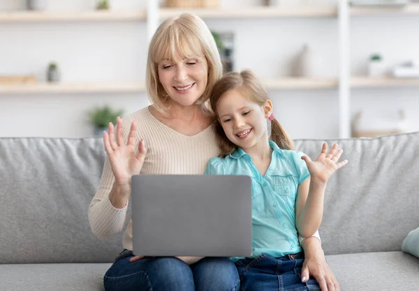 Бабуся і дівчинка мають відеокасету за допомогою ноутбука розмахуючи руками. — стокове фото