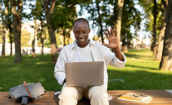 Αφροαμερικάνος φοιτητής κουνώντας χέρι-με-laptop βιντεοκλήση, μάθηση σε απευθείας σύνδεση έξω στο πάρκο — Φωτογραφία Αρχείου