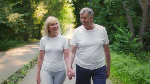 Ενεργός τρόπος ζωής για ηλικιωμένους συζύγους. Ευτυχισμένο ώριμο ζευγάρι περπατώντας μαζί σε δημόσιο πάρκο κρατώντας τα χέρια — Αρχείο Βίντεο
