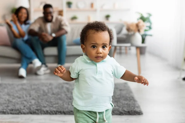 Schattige baby peuter wandelen in de woonkamer het maken van eerste stappen — Stockfoto