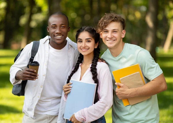 Счастливые иностранные студенты, которые отдыхают после занятий и позируют с ноутбуками на открытом воздухе в кампусе — стоковое фото