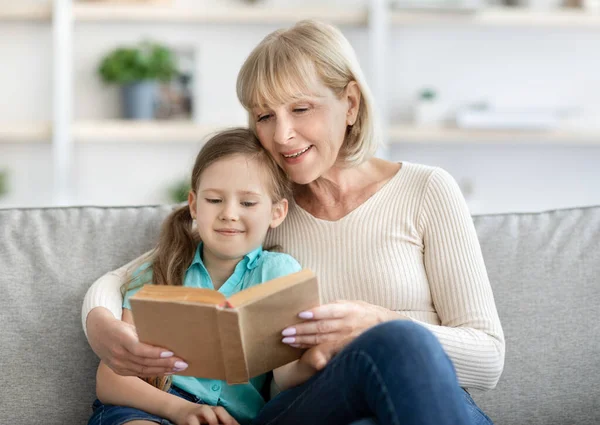 Portret szczęśliwej dojrzałej kobiety i wnuczki czytającej książkę — Zdjęcie stockowe