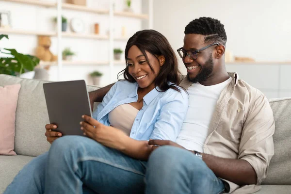 Africký americký pár sedí na gauči, pomocí tabletu — Stock fotografie