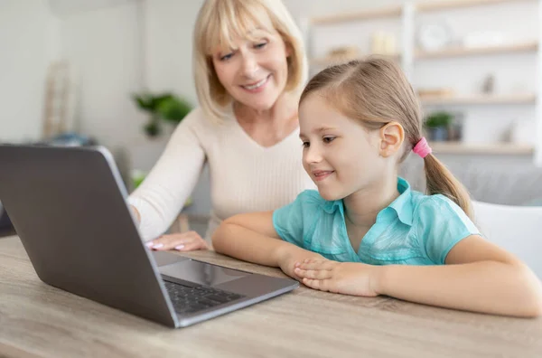 Mujer madura feliz y nieta utilizando el ordenador portátil —  Fotos de Stock
