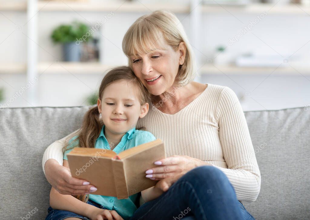 Portrait of happy mature woman and granddaughter reading book