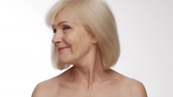 Close up portret pozytywnej starszej blondynki potrząsając głową, bawiąc się włosami i śmiejąc się, zwolniony ruch — Wideo stockowe