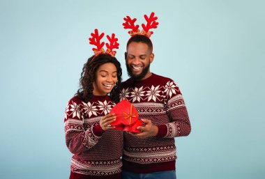 Ne güzel bir sürpriz. Erkek arkadaşı onu kucaklarken Afrikalı Amerikalı kadın hediye kutusunu açıyor ve gülümsüyor.