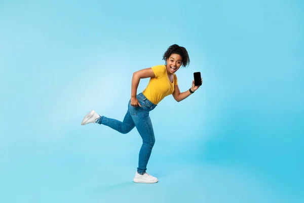 Boldog fiatal afro nő üres okostelefon fut a kék háttér, mockup honlap vagy mobil app — Stock Fotó