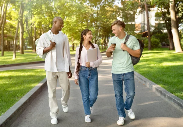 Tři multiraciální středoškoláci chodící po studiu a mluvící v univerzitním kampusu venku — Stock fotografie