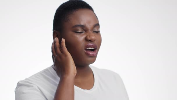 Kulak çınlaması. Hasta Afrika kökenli Amerikalı kadın portresi kulak ağrısı çekiyor, acı dolu kafasına dokunuyor, beyaz stüdyo geçmişi var. — Stok video