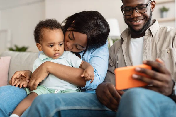 Afro-Amerikaanse familie met behulp van mobiele telefoon met baby thuis — Stockfoto