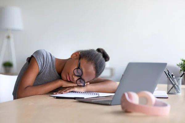 Втомився підліток афро-американська школярка в окулярах навчається вдома з ноутбуком, спить на клавіатурі — стокове фото