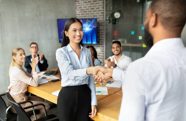 Jefe negro sacudiendo las manos y felicitando a la empleada asiática con éxito empresarial — Foto de Stock