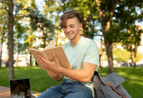 Oktatási koncepció. Tinédzser diák srác olvasás könyvet a szabadban, és felkészülés a vizsgákra, ül az egyetemen — Stock Fotó