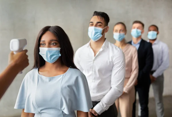 Person With Contactless Thermometer Checking Temperature For Group Of Workers In Masks — 스톡 사진