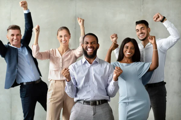 Équipe réussie. Groupe de collègues multiraciaux célébrant les réalisations commerciales avec des poings levés — Photo