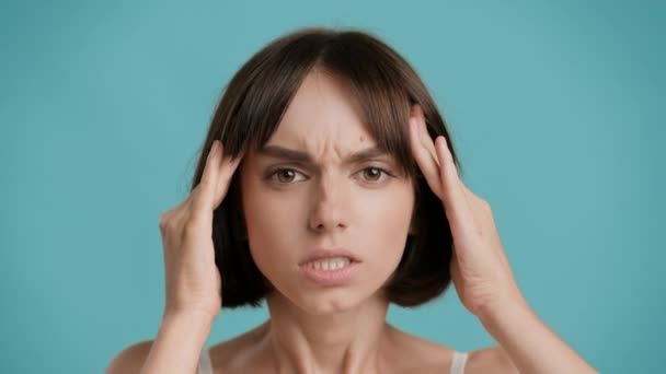 痛みを伴う頭痛を持つ女性は、寺院、青の背景をマッサージ — ストック動画