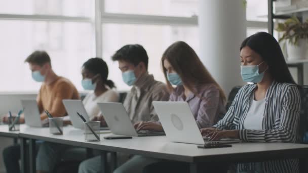 Új normál és offline tanulmányi koncepció. Különféle egyetemisták csoportja, akik védőmaszkot viselnek, és laptopon gépelnek. — Stock videók