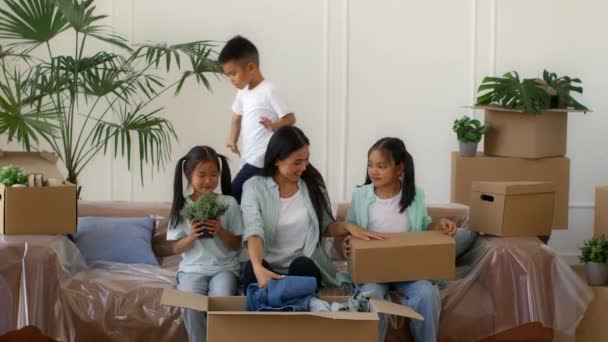 Asiática familia mudanza casa embalaje cajas y divertirse en interior — Vídeo de stock