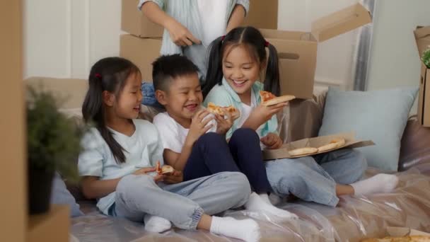 Japonská děti jíst pizzu zatímco matka balení stěhování boxy vnitřní — Stock video