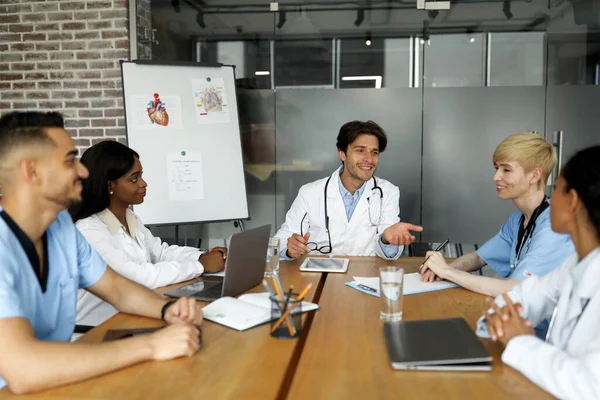 Hombre guapo médico con tableta digital hablando con sus colegas — Foto de Stock