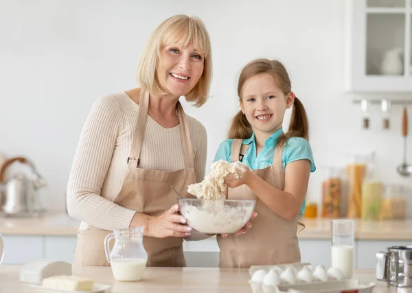 Glückliche Seniorin und ihre Enkelin beim Teigzubereiten — Stockfoto