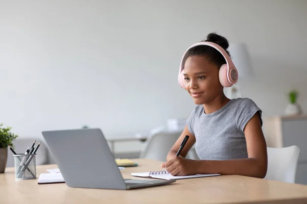 Happy adolescent afro américaine étudiante avec écouteurs étudiant à la maison regarder leçon en ligne — Photo